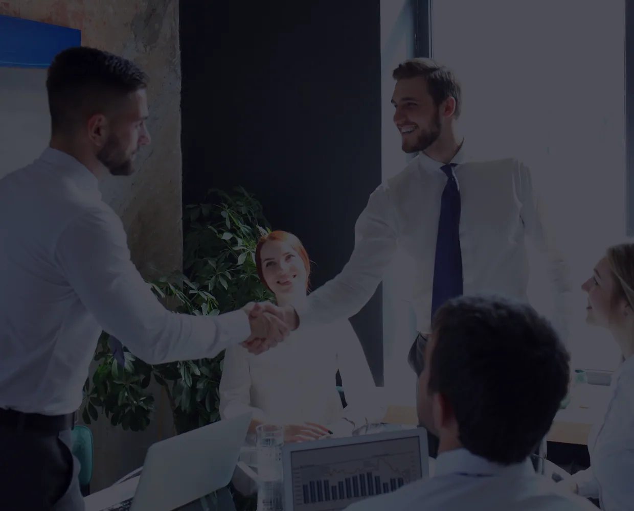 Colleagues shake hands across a meeting table.